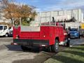 A red 2013 Chevrolet Silverado 3500HD with a silver bed and toolboxes visible on the sides parked in an industrial area