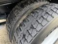 Close-up of a pair of heavily treaded tires on a 2012 International DuraStar 4300 showing wear and dirt on the rubber surface