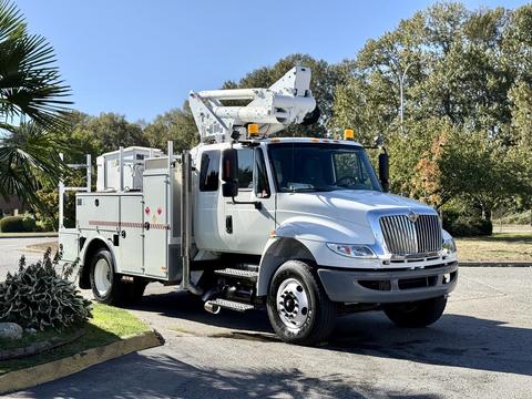 A 2010 International 4300 bucket truck with an extended aerial lift and tool storage compartments on the sides