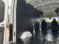 A 2020 Ford Transit 250 cargo van with an empty interior featuring a black wall panel and two front seats visible in the foreground