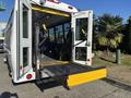 A 2017 Ford Transit-350 with an open rear door revealing a wheelchair ramp extending outward and accessible seating inside the vehicle
