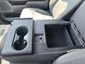 Interior console of a 2021 Ford F-150 featuring cup holders and a storage compartment with a textured surface