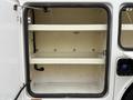 A 2015 Ford F-450 with an open storage compartment featuring two shelves and a clean interior