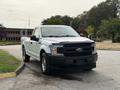 A 2018 Ford F-150 with a white exterior and black hood is parked at an angle showcasing its front and side profile