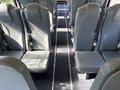 Interior view of a 2013 International CE300 bus featuring rows of gray vinyl seats with seatbelts and a central aisle