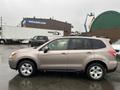 A 2016 Subaru Forester in bronze color parked with side view showcasing its compact SUV design and five-spoke wheels