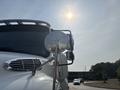 A 2010 Freightliner M2 106 truck with a prominent side mirror reflecting sunlight