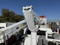 A 2010 International 4300 bucket truck equipped with a telescoping lift arm and a white boom for overhead work