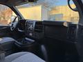Interior view of a 2015 GMC Savana showing the driver's seat dashboard and controls with fabric upholstery and cup holders