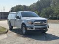 A 2019 Ford F-150 in white with chrome accents parked on a gravel surface featuring a truck bed cover and alloy wheels