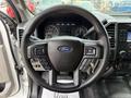 The steering wheel of a 2018 Ford F-150 featuring the Ford logo and various control buttons