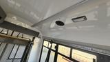 Interior view of a 2021 Ford Transit showing a smooth white ceiling and a circular speaker mounted in the center