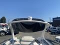 A 2013 Larson 238 boat with a white and black bimini top and seating area visible in the foreground