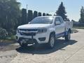 A white 2017 Chevrolet Colorado pickup truck with a front-mounted winch and a utility bed in blue on the side