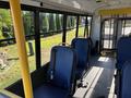 Interior view of a 2017 Ford Transit-350 showing blue seats and a yellow pole with a secured area at the back for additional space