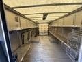A 2012 Ford Econoline cargo van interior with empty shelves and a front loading area showing metal racks and walls