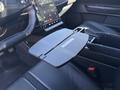 A black foldable tray attached to the center console of a 2023 Fisker Ocean vehicle