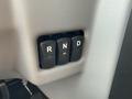 A gear shift panel with three buttons labeled R N and D arranged vertically with the D button illuminated in orange