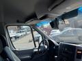 The interior of a 2010 Mercedes-Benz Sprinter featuring the dashboard steering wheel and driver side view with a mounted monitor and sun visor