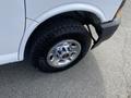 A close-up view of a 2022 GMC Savana's front wheel showcasing a chrome rim and rugged tire tread