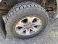 Close-up of a rugged tire mounted on a silver alloy wheel with the inscription Wrangler visible on the tread of the tire