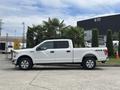A white 2017 Ford F-150 pickup truck parked with doors closed and a chrome grille, featuring 4x4 decals on the rear side