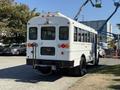 A white 2013 International CE300 school bus viewed from the rear showcasing its windows and tail lights