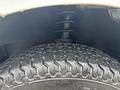 Close-up of the tire and suspension system of a 2010 Suzuki Carry showcasing the tread pattern and coil spring support
