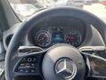 Steering wheel of a 2024 Mercedes-Benz Sprinter showing controls and dashboard display with speed and other gauges