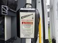 A 2023 Ford Transit van with a safety sign attached to a wall inside, indicating potential dangers associated with the equipment and emphasizing safety precautions