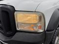 Close-up of a 2006 Ford F-450 headlight showing raindrops on the surface with a yellowish light glowing from the lens
