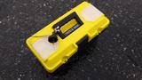 A yellow tool box labeled Tools Box with a black handle sitting on a wet surface