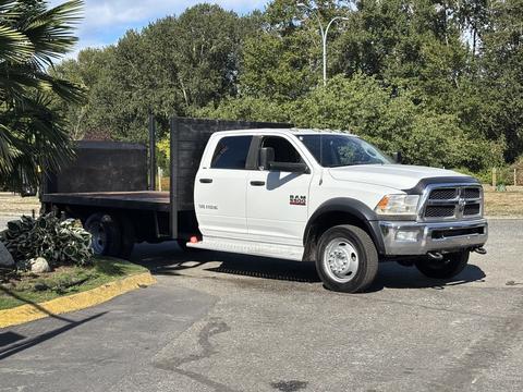 A white 2014 RAM 5500 truck with a flatbed attached parked at an outdoor location
