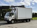 A 2014 Hino 195 truck with a white box cargo area and a gray cab parked on a paved surface