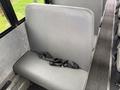 A gray bus seat with a black seatbelt attached, sitting in an interior space designed for passenger transport