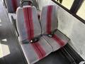 Seating area of a 2011 Freightliner B2 with two gray upholstered seats featuring red stripes and seat belts
