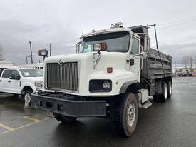 A 2003 International 5600i dump truck with a white cab and a black dump bed parked at an outdoor location