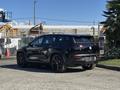 A black 2023 Fisker Ocean SUV is parked, showcasing its modern design, sleek lines, and large black wheels