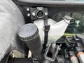 A black diesel cap and a white fluid reservoir attached with a strap on the side of a tractor engine compartment