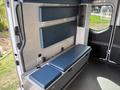 Interior of a 2020 Mercedes-Benz Sprinter 2500 featuring a blue padded bench with storage below and wall-mounted padded panels