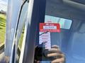 A red certificate of approval sticker on the window of a 2014 Hino 195 truck indicating monthly status and a unique identification number