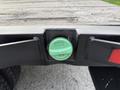 A close-up of a green fuel cap on the rear of a 2020 Ford F-550 truck with a flatbed design and visible tire tread marks