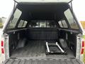A 2014 Ford F-150 with an open truck bed featuring a black liner and a foldable metal rack positioned on one side