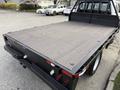 A 2020 Ford F-550 flatbed truck with a wooden bed surface and rear lights visible in the foreground