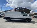 A white 2019 Ford Transit van with a roof rack and black trim parked sideways