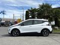 A white 2023 Chevrolet Bolt EV is parked with its side facing the viewer showcasing its sleek design and modern features