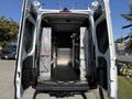 A 2023 Mercedes-Benz Sprinter 2500 with open rear doors revealing a spacious interior equipped with shelving and storage compartments