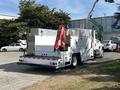 A 2006 International 4300 service truck with a flatbed and utility boxes on the sides equipped with a hydraulic crane and safety lights