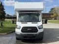 A white 2016 Ford Transit van with a high roof and large front grille is parked facing forward