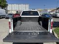 The image shows the open bed of a white 2014 Ford F-150 with a black textured liner and no cargo inside